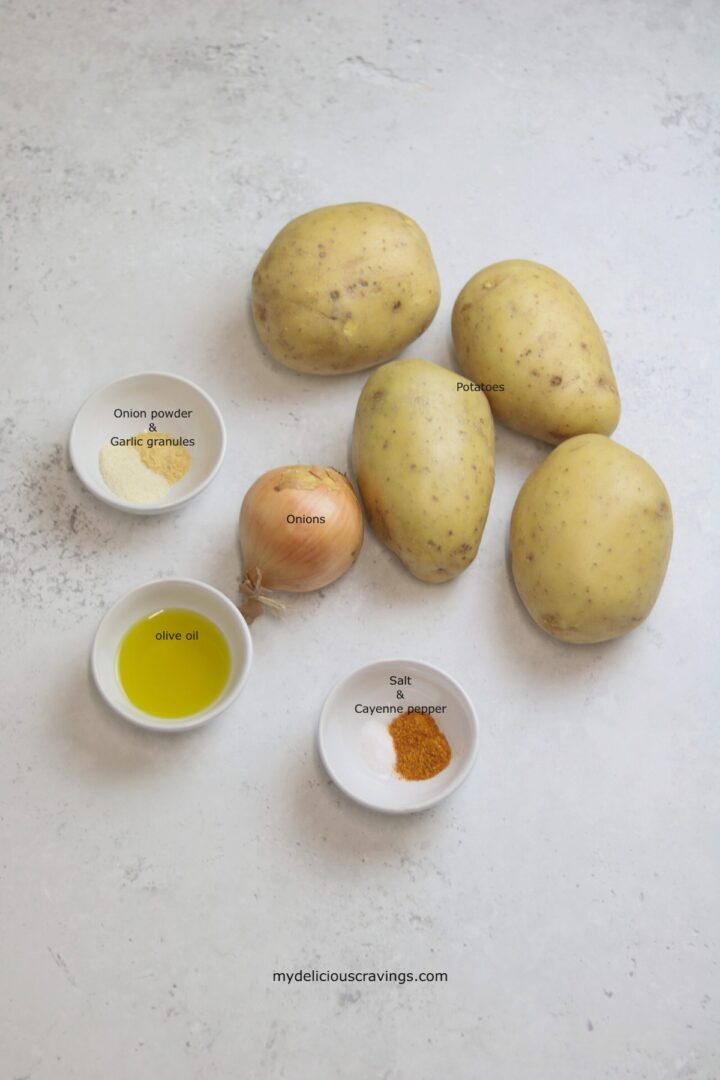 Ingredients to make potatoes and onions recipe placed on a white marble surface.