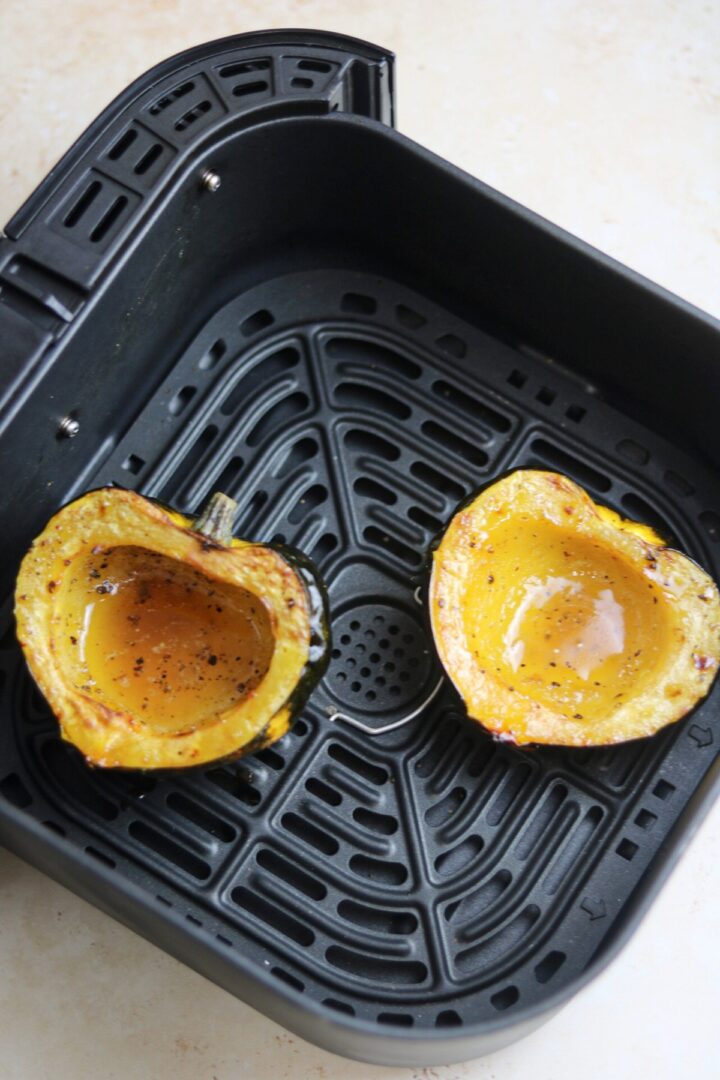 two halves of acorn squash in air fryer basket