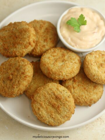 8 fish cakes on a white plate and a dipping sauce.