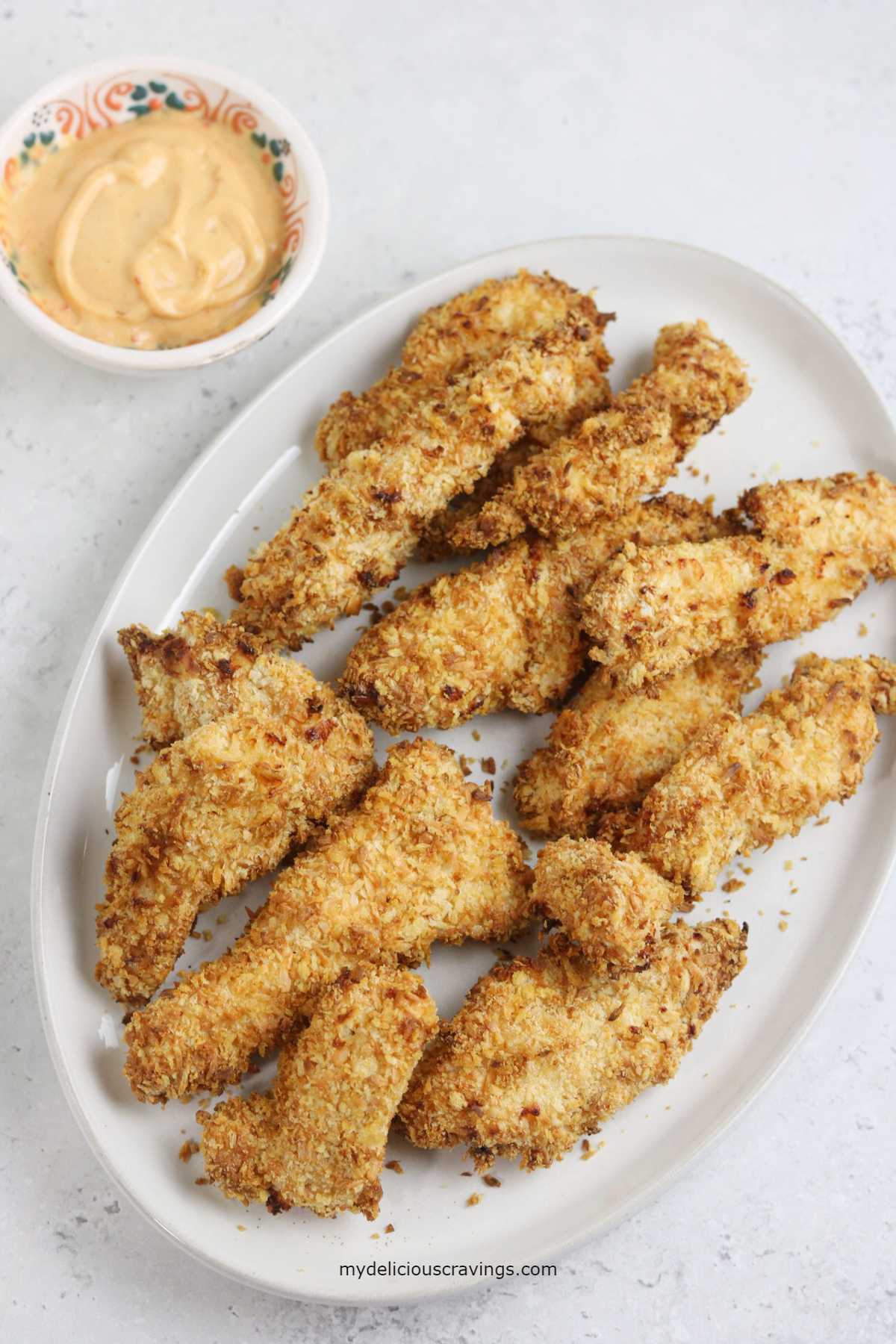 air fryer coconut chicken tenders served with dipping sauce. 